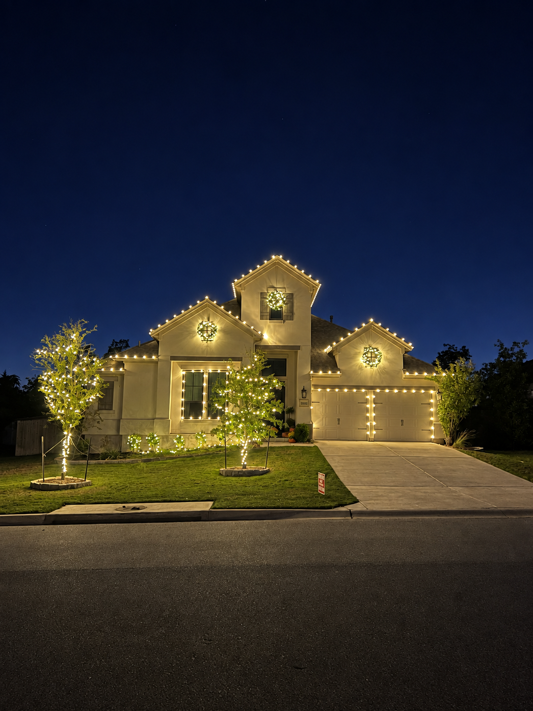 Three-gabled Bastrop home glowing with warm Christmas lights